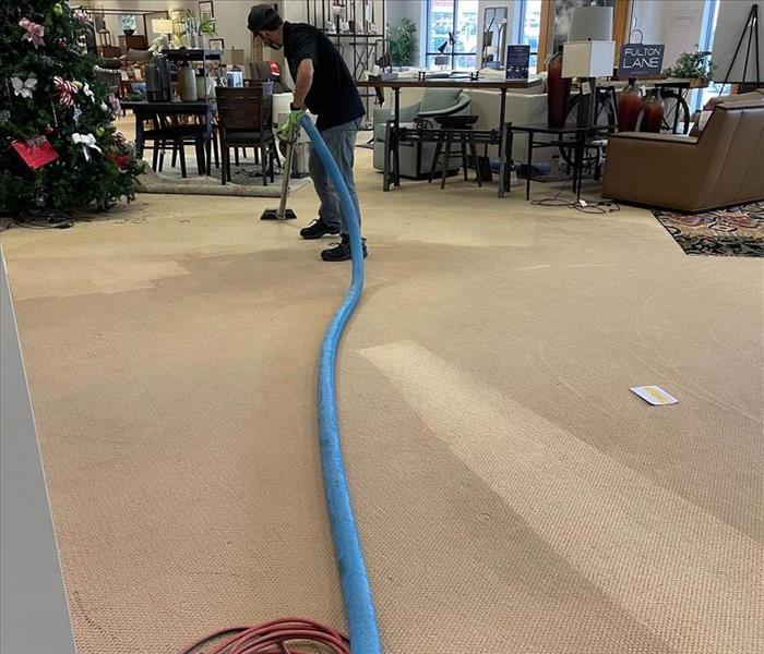 Man extracting water from wet carpet with what looks like a vacuum water extractor