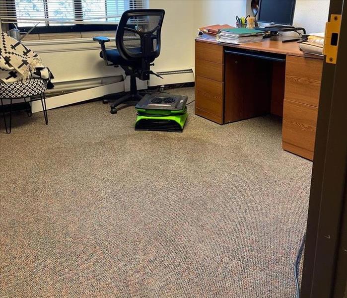 office with wet carpet and an air mover set up working to dry the affected area
